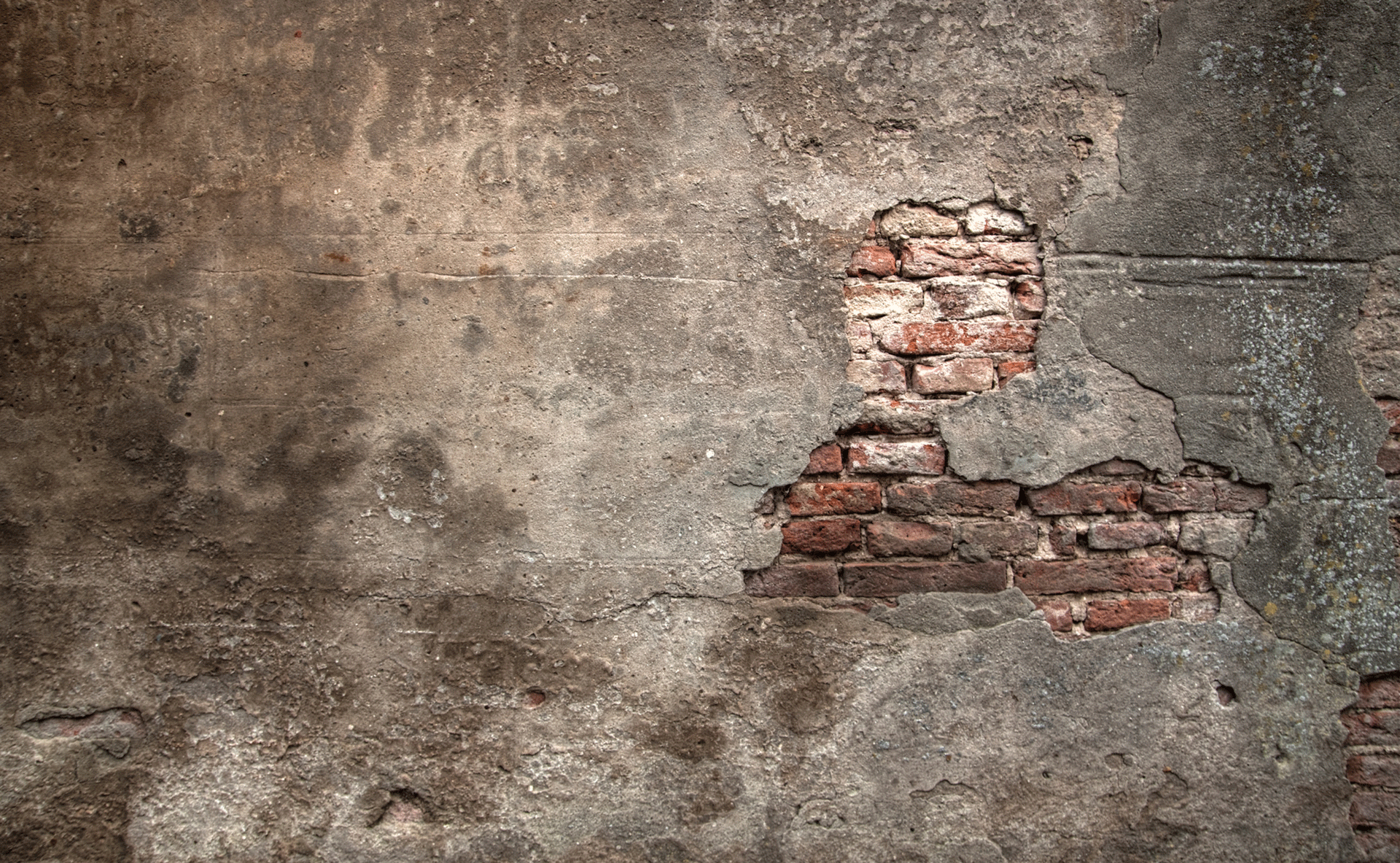 An old plastered wall with the plaster cracking exposing old bricks