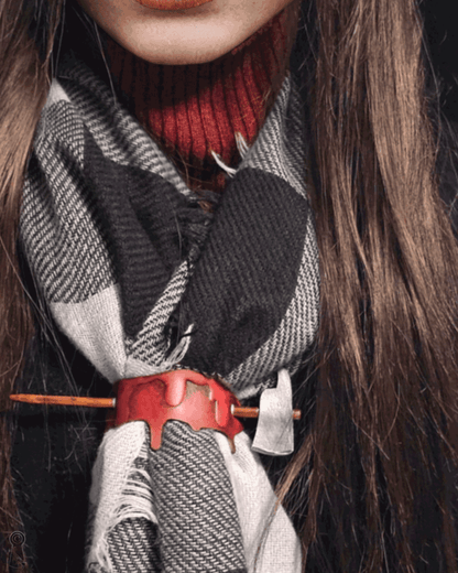 Person wearing a plaid scarf, with a blood drop and axe hairpion decorating the scarf.