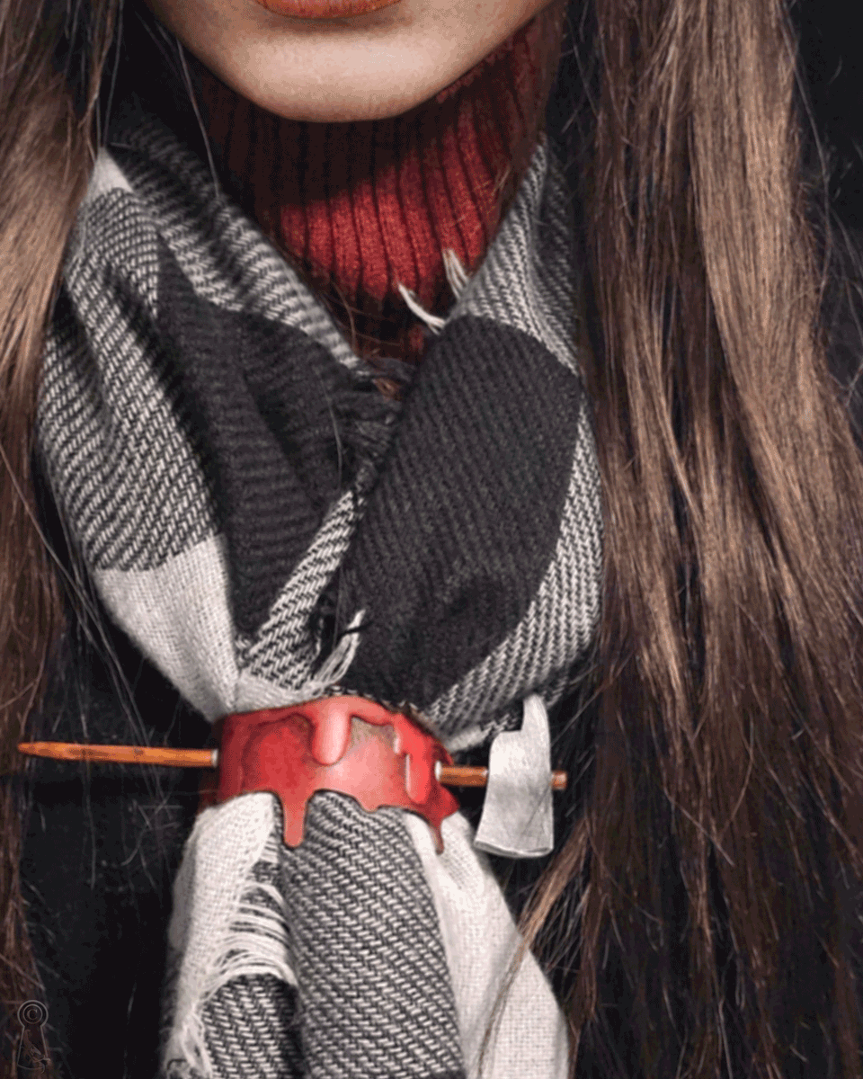 Person wearing a plaid scarf, with a blood drop and axe hairpion decorating the scarf.