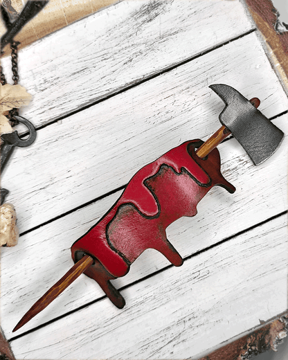 Axe with wooden handle through a blood drip on a white wooden surface