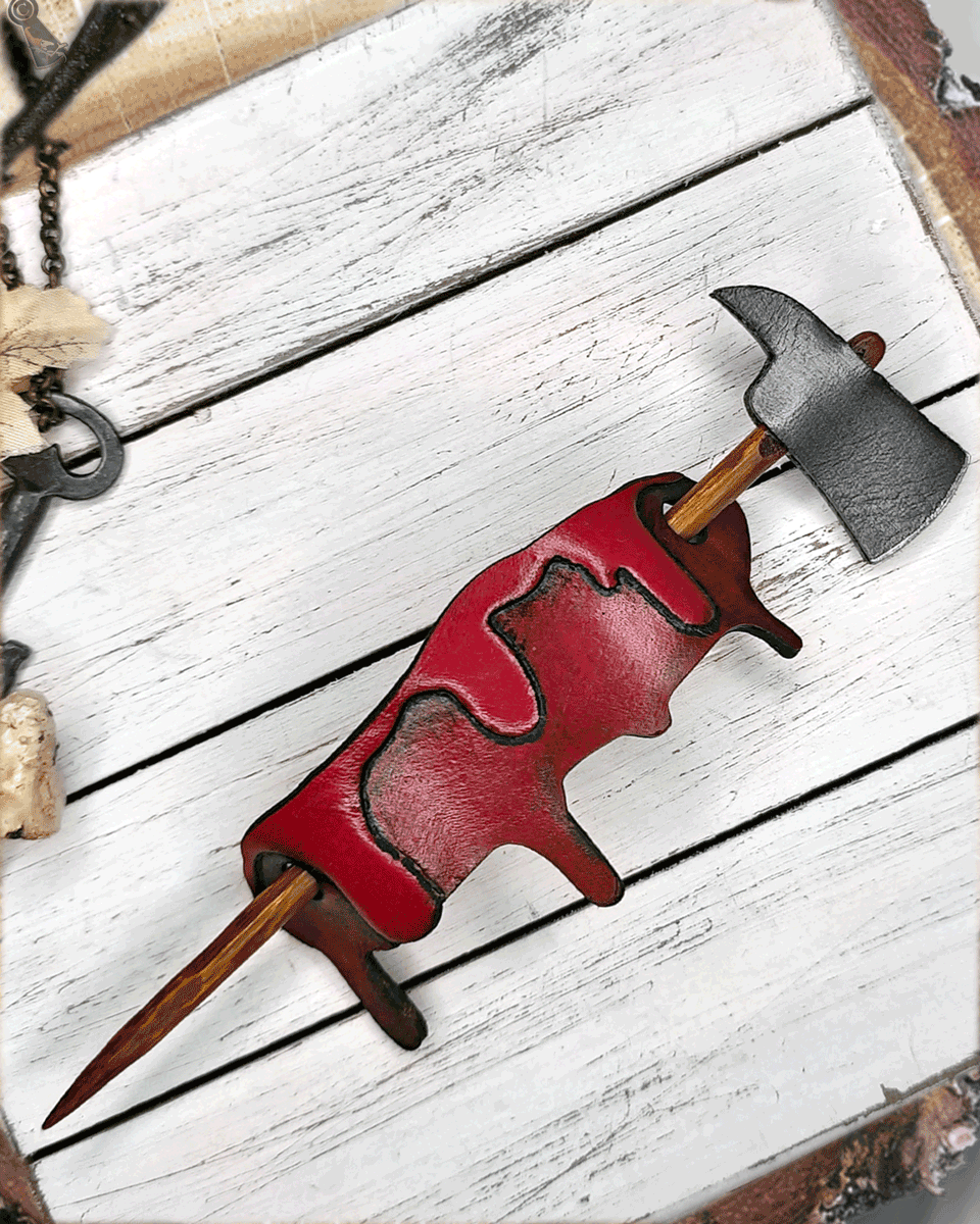 Axe with wooden handle through a blood drip on a white wooden surface