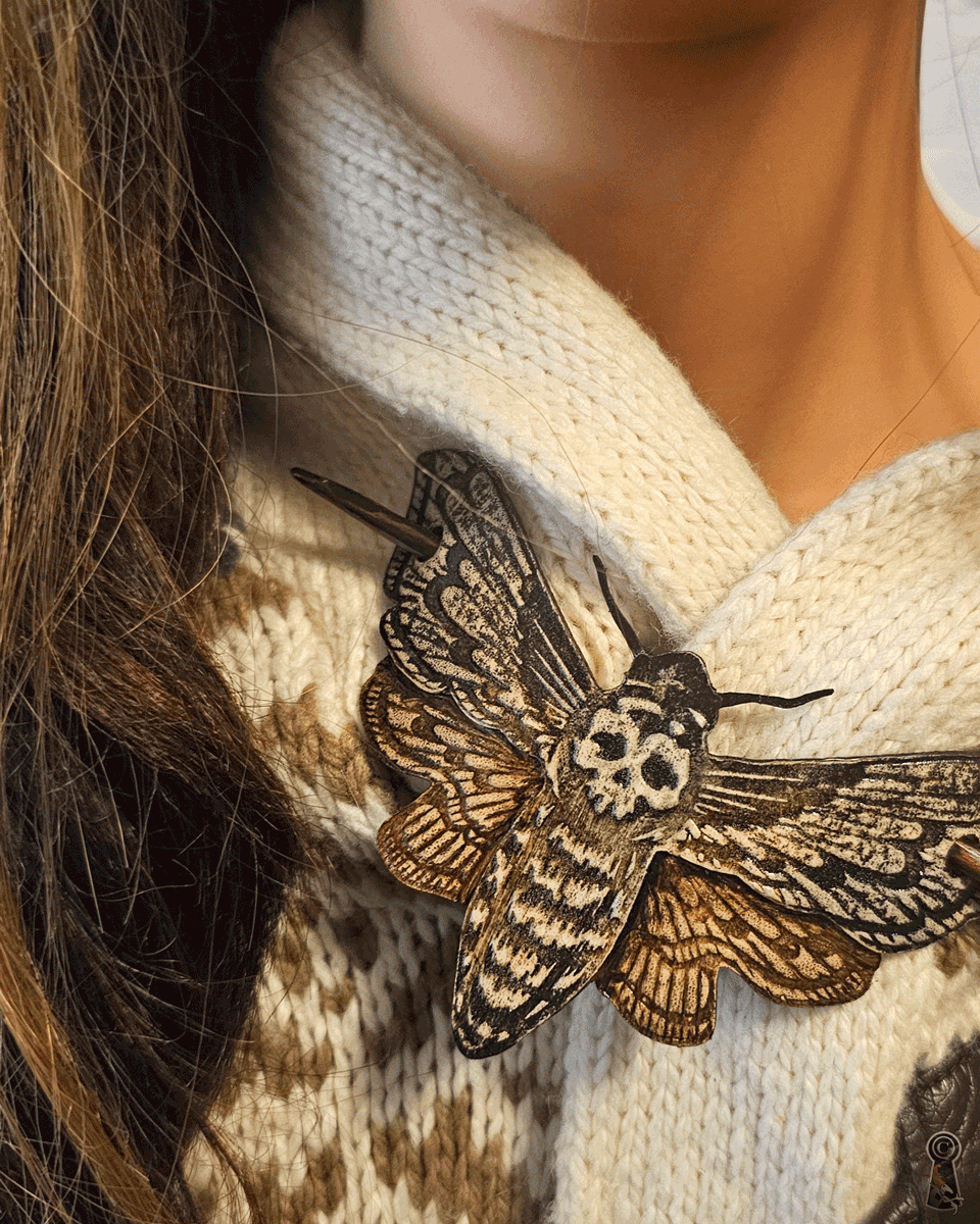 Close-up of a person wearing a white sweater with a large moth brooch.