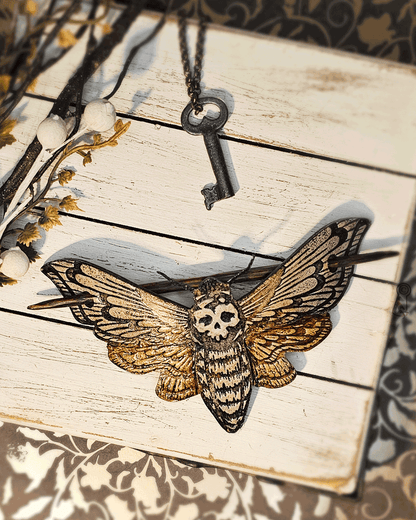 Moth-shaped hair slide with skull design placed on a wooden surface.