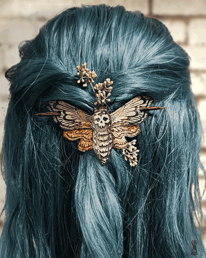 Blue hair with a decorative death's head moth hairpin against a brick wall background