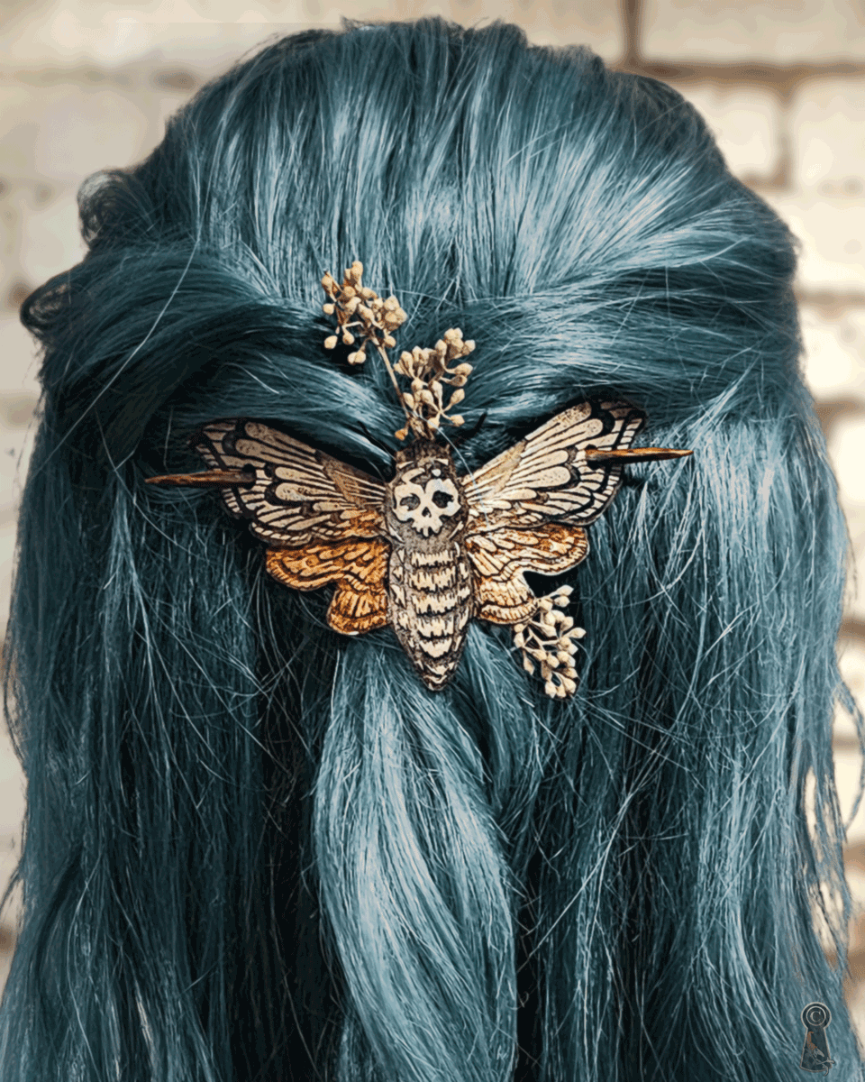 Blue hair with a decorative death's head moth hairpin against a brick wall background