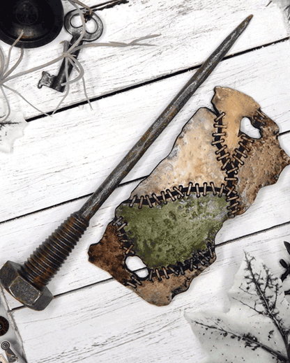Long metal bolt with a hair slide of stitched patches of colors separated on a white wooden surface.