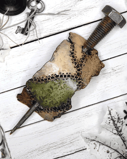 Long metal bolt through a hair slide of stitched patches of colors on a white wooden surface.