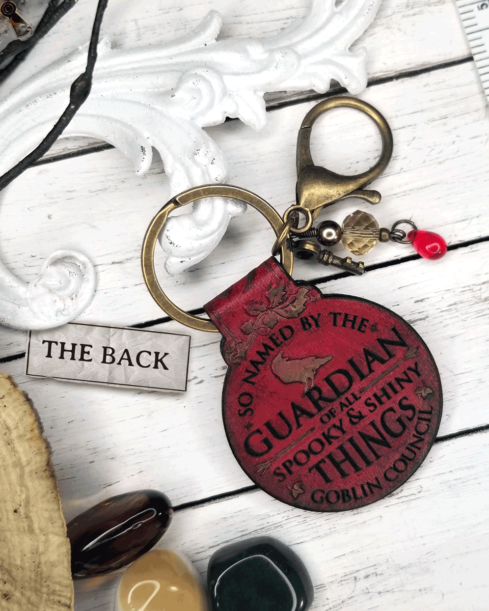 Red leather keychain with text on a white wooden surface