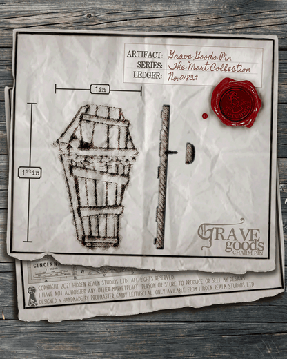 Aged paper with an illustration of a coffin lapel pin and it's measurements on a wooden surface.