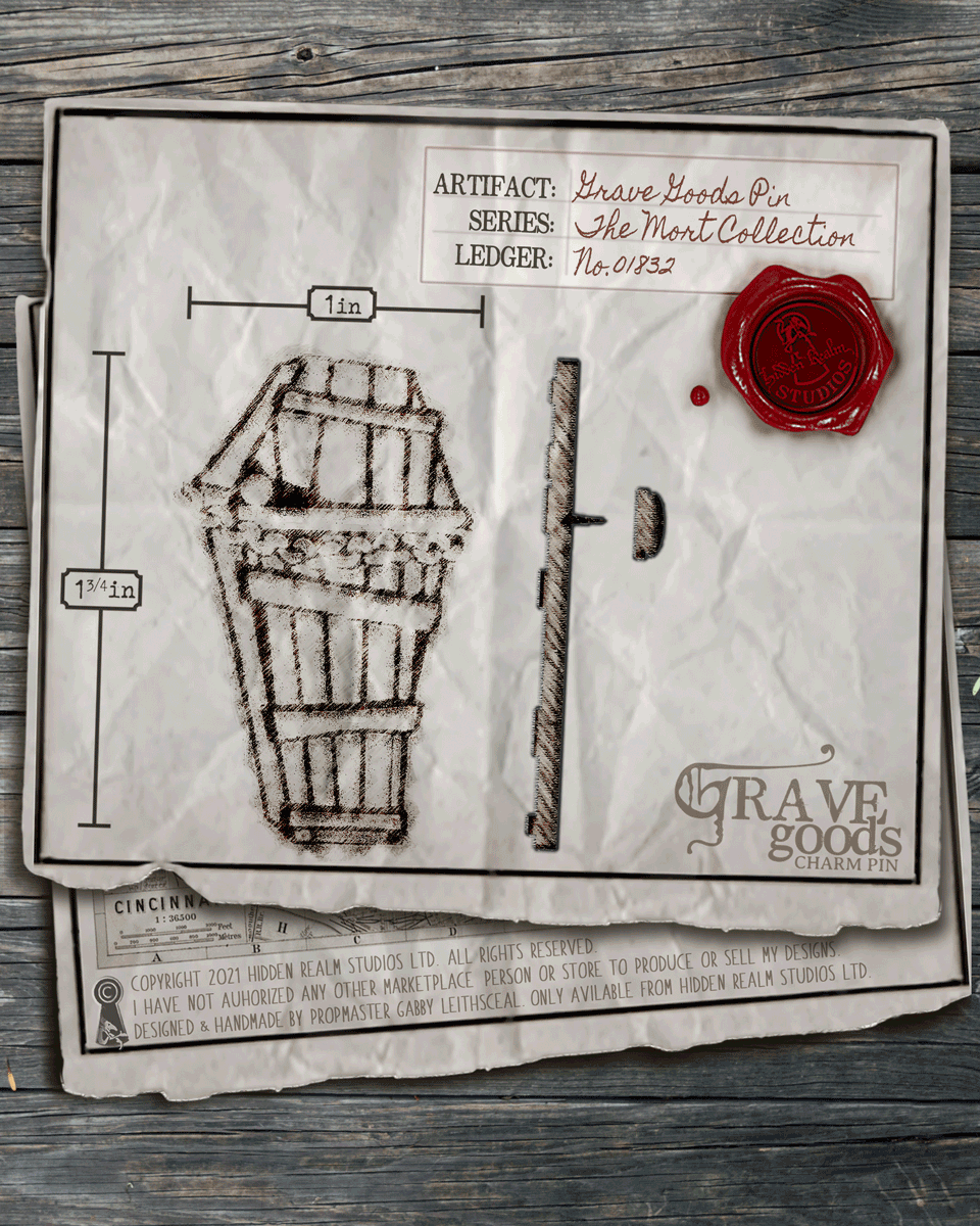 Aged paper with an illustration of a coffin lapel pin and it's measurements on a wooden surface.