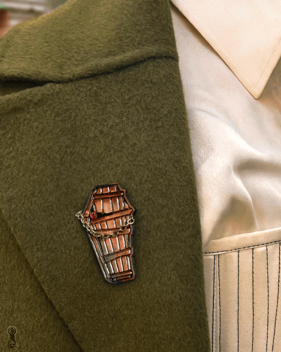 Wooden coffin-shaped brooch on a green coat