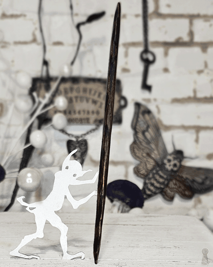 Close up of a wood hair stick photographed as a staff with a white silhouette figure holding it on a rustic background