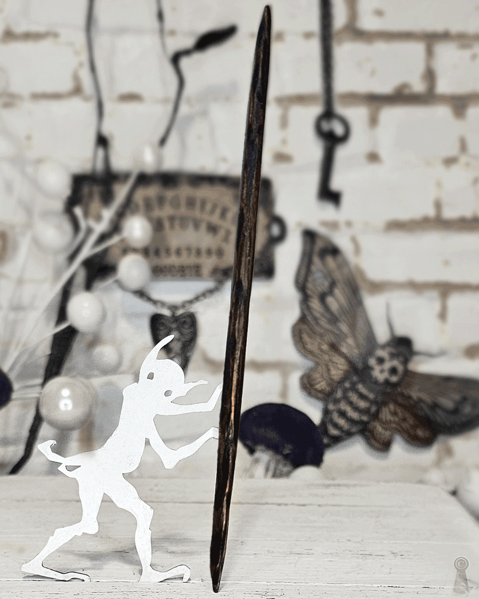 Close up of a wood hair stick photographed as a staff with a white silhouette figure holding it on a rustic background