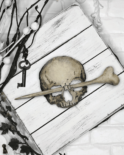Leather skull and a wood, resin bone on a white wooden surface with decorative elements.