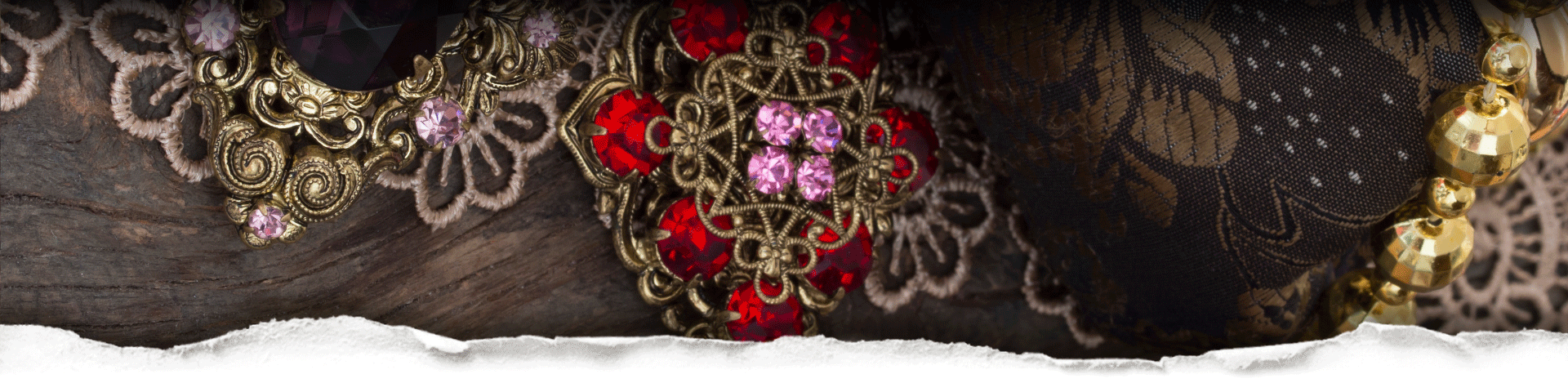 Close-up of decorative brooches on a textured fabric background behind torn paper