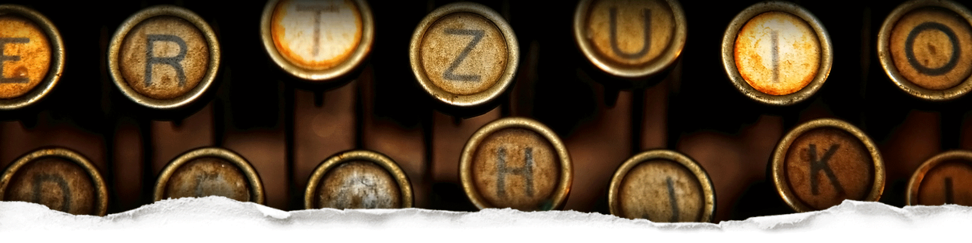 Close-up of a vintage typewriter round letters keys behind torn paper
